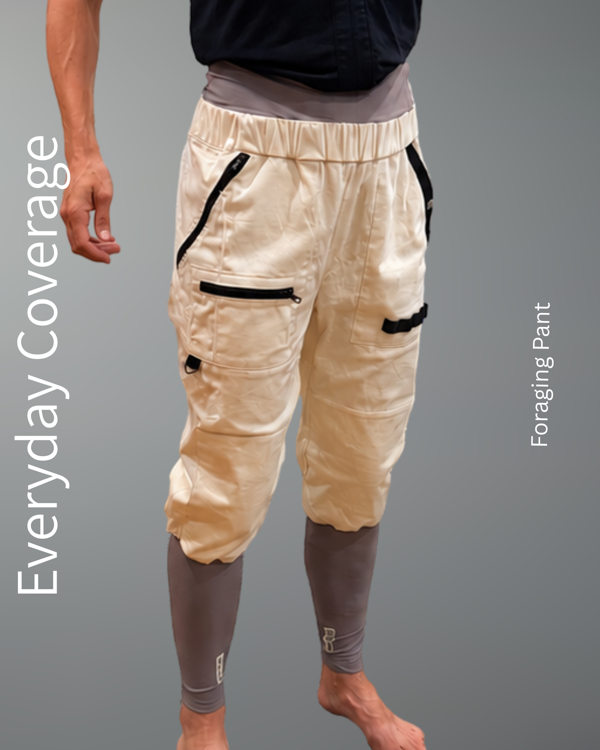 A person modeling a pair of loose offwhite cargo-style pants with black zipper accents and gray compression sleeves, shown against a plain gray background with vertical text reading 'Everyday Coverage' and 'Foraging Pant.'.